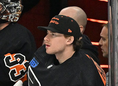 Carter Hart, NHL goaltender sits on bench watching the action